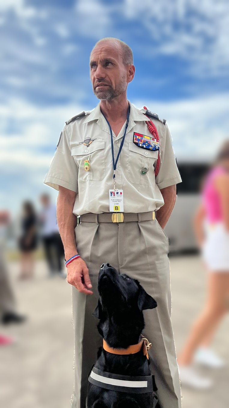 Un militaire en uniforme et son chien d’assistance, un labrador noir